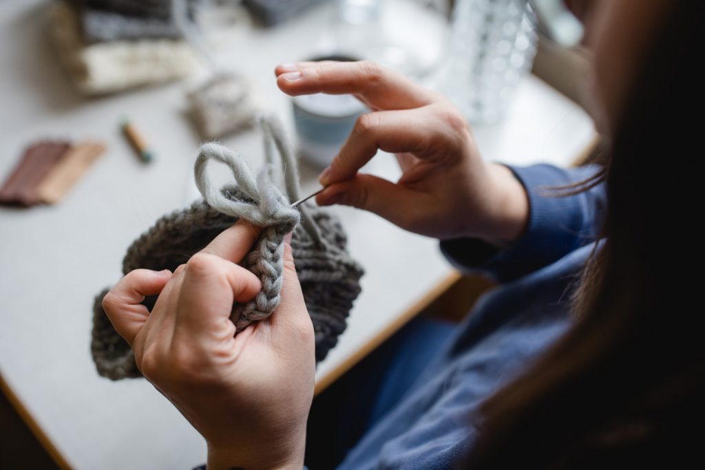 Feinste Handarbeit. Mit einer großen Teppichnadel vernäht Simone Angerer die Merino Wolle. Foto von Nina Bröll.